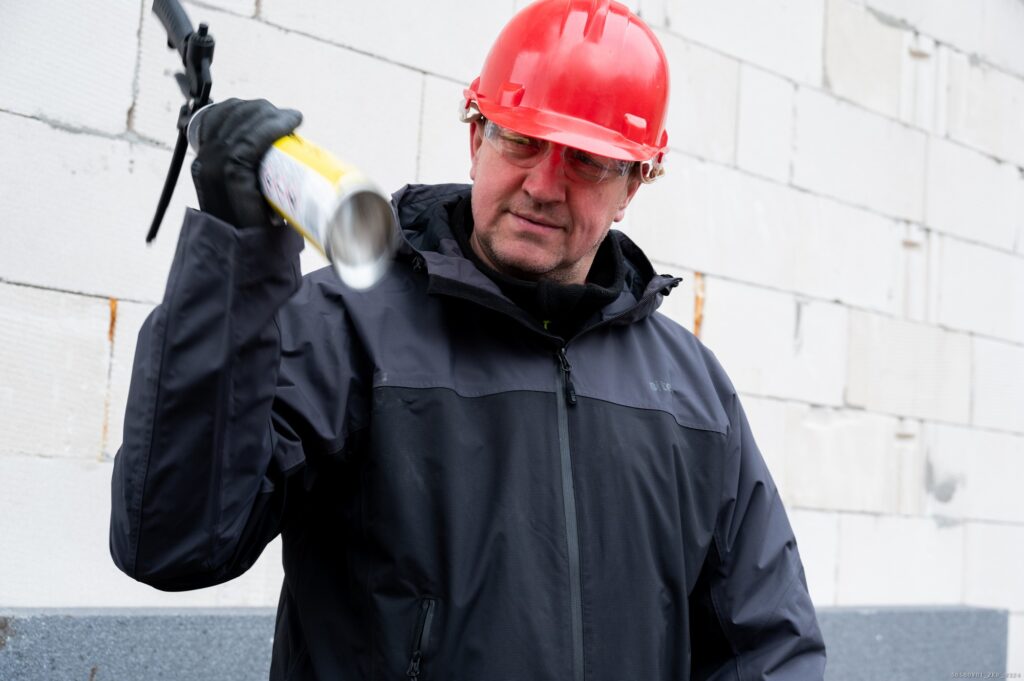Construction worker shake the Tytan Professional foam adhesive before applying to the styrofoam